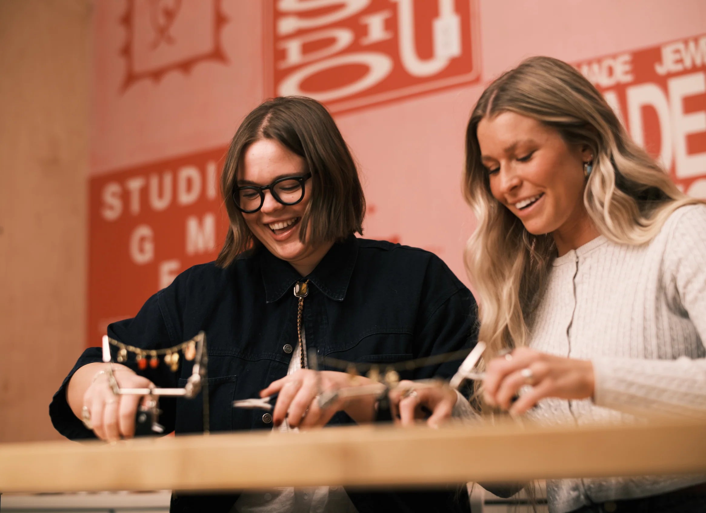Friends laughing at a Gem Studio silversmithing workshop bench